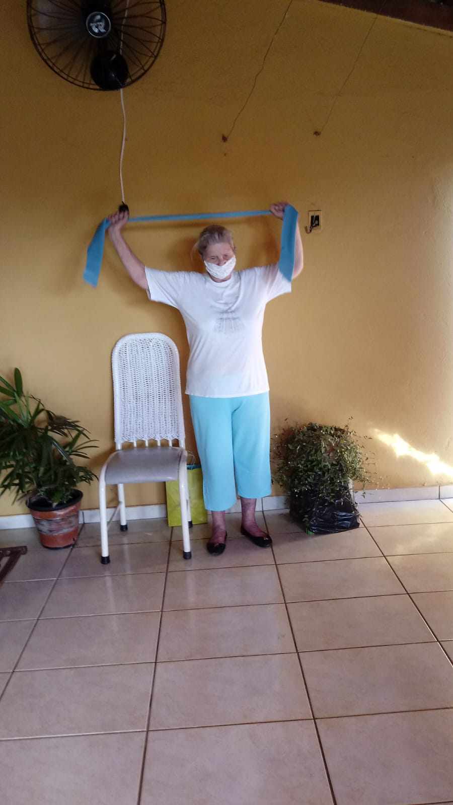 Paciente realizando exercício com faixa elástica em casa